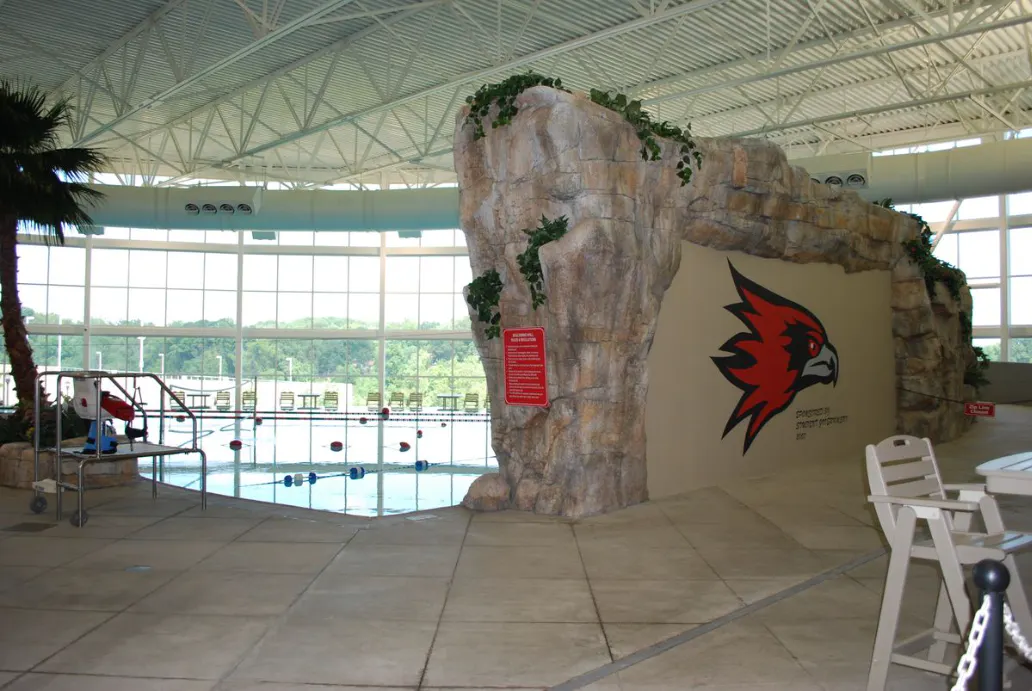 Indoor pool area with a rock feature wall and Redhawks logo