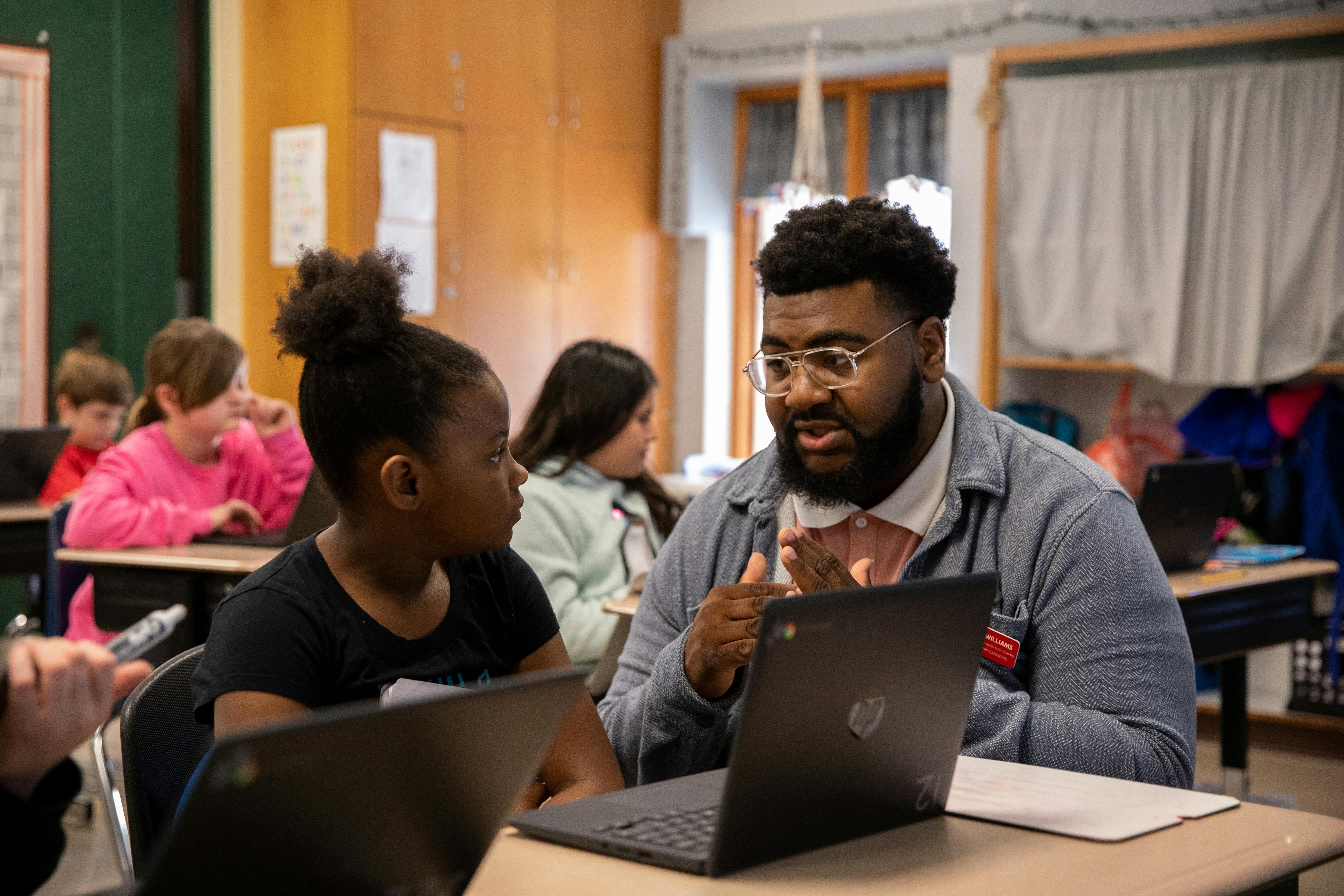 a semo student teaching candidate kneels next to a students desk helping with a math problem