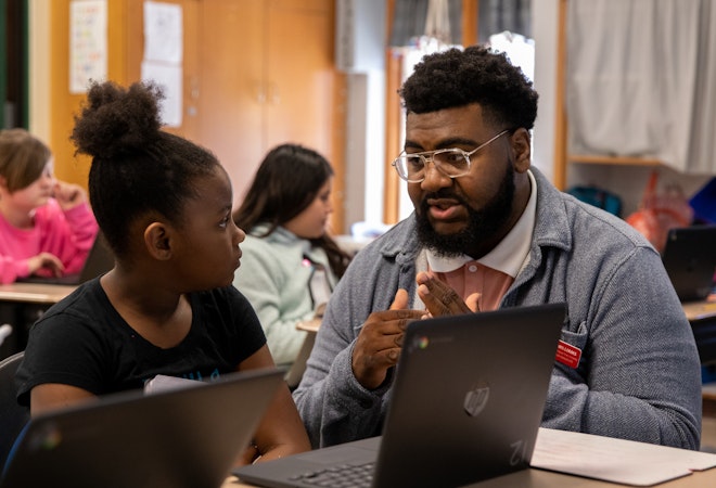 a semo student teaching candidate kneels next to a students desk helping with a math problem