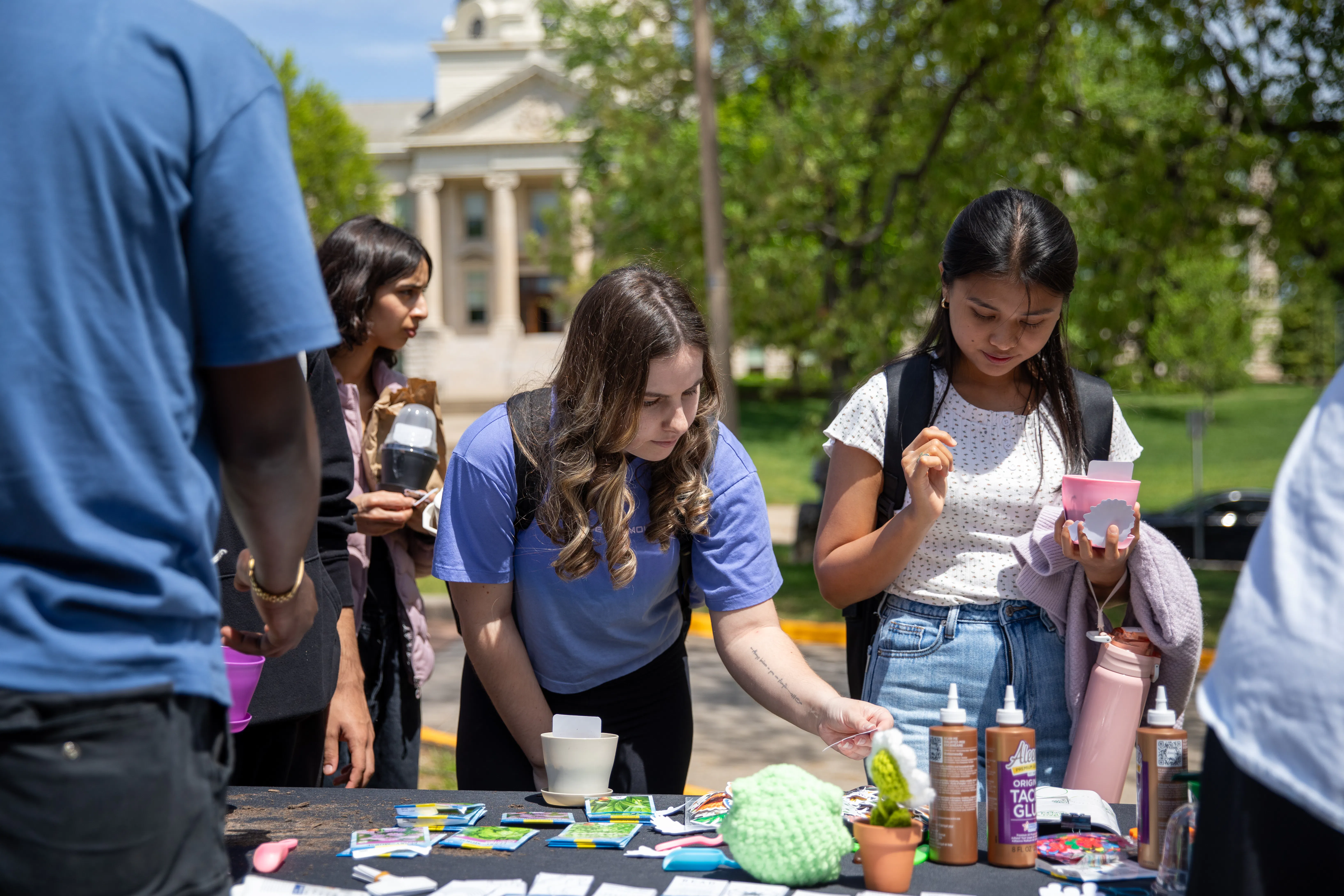 two students plant their own herbs in small pots they've decorated at an on campus earth day event
