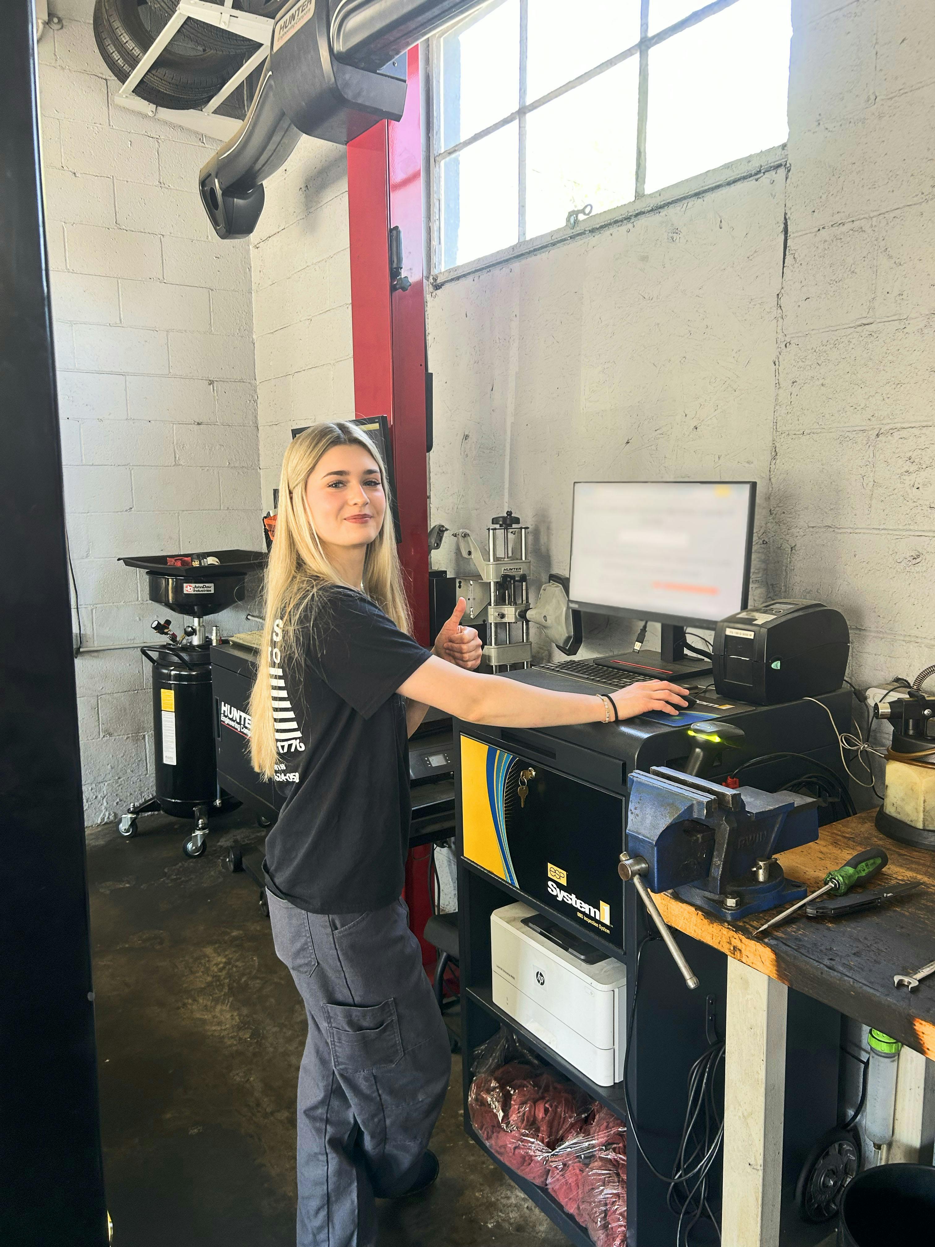 Woman standing in automotive shop, working on a computer