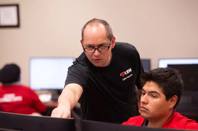 Male cyber security student receiving instruction from a cyber security professor.