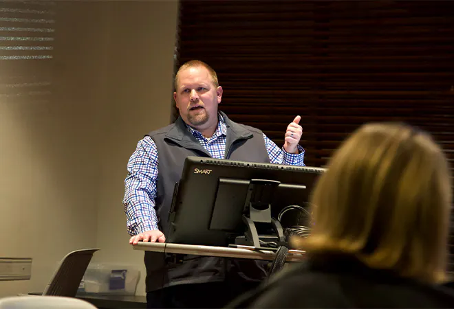 A masters student presenting at the front of a room.